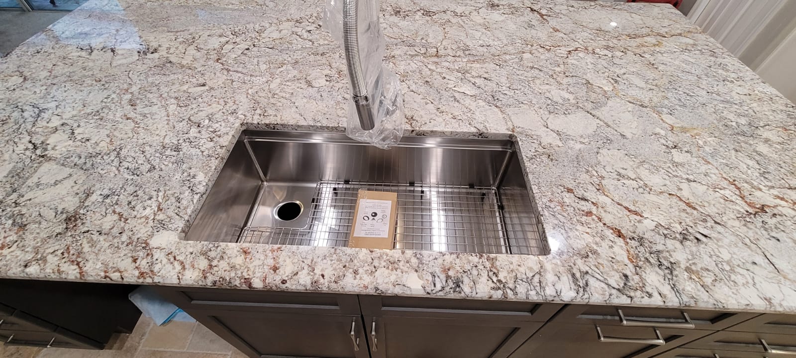 A stainless steel sink with a granite counter top.